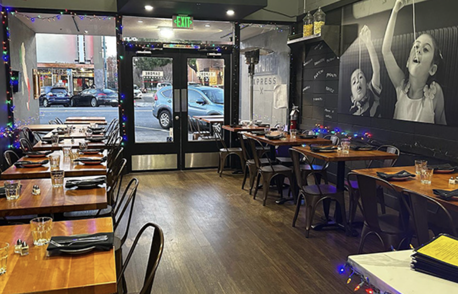 Inside Sapore Express in San Mateo — dining room with string lights, pasta mural and the front door